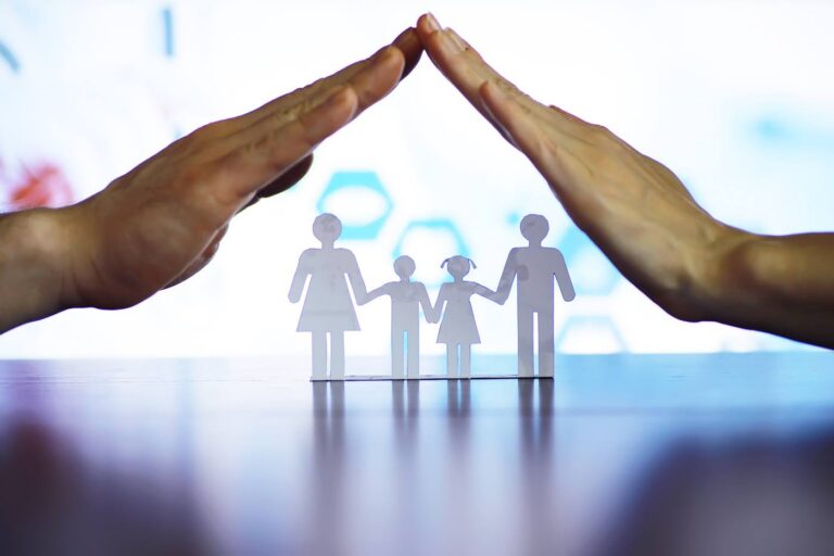 Hands protecting a paper family, symbolizing estate planning protection