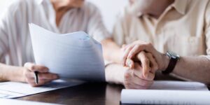 Senior couple holding hands while reviewing probate avoidance documents