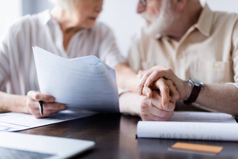 Senior couple holding hands while reviewing probate avoidance documents