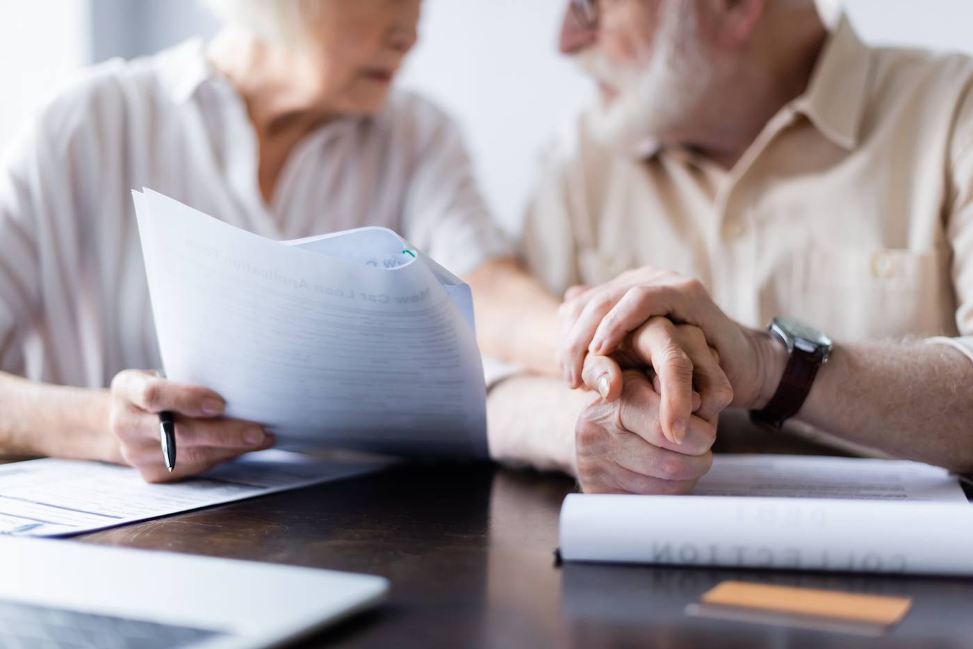 Senior couple holding hands while reviewing probate avoidance documents