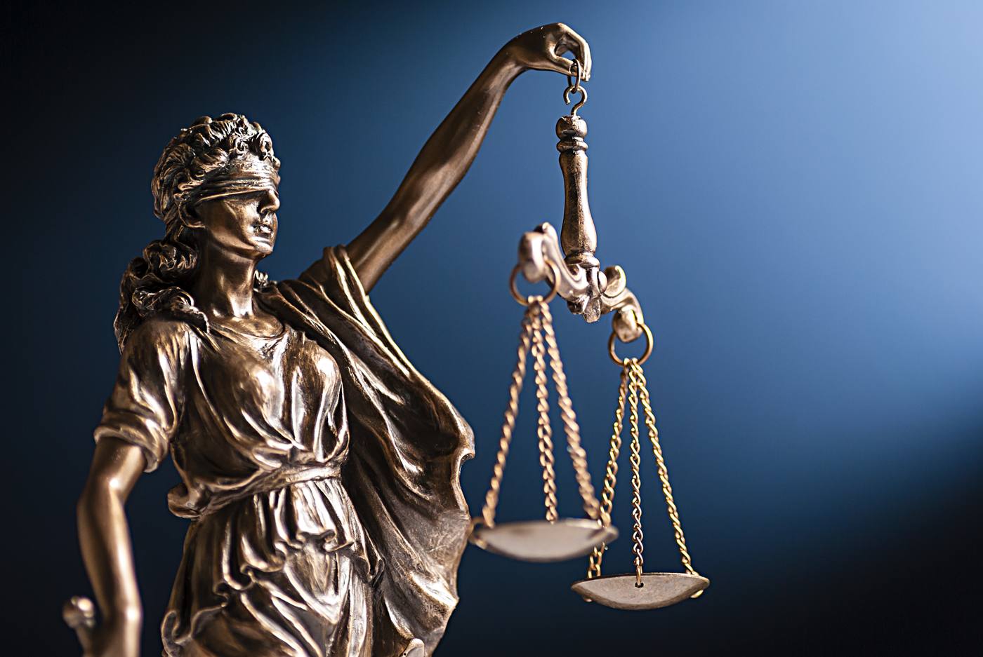 Scales of justice statue against a dark blue backdrop