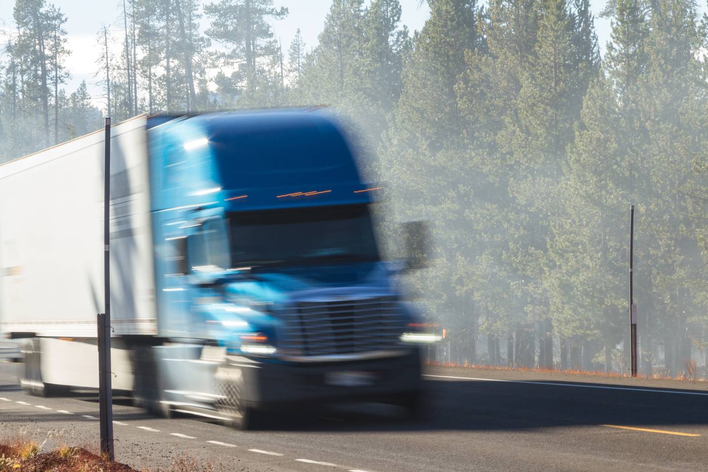 Semi truck moving at speed on a forested mountain highway