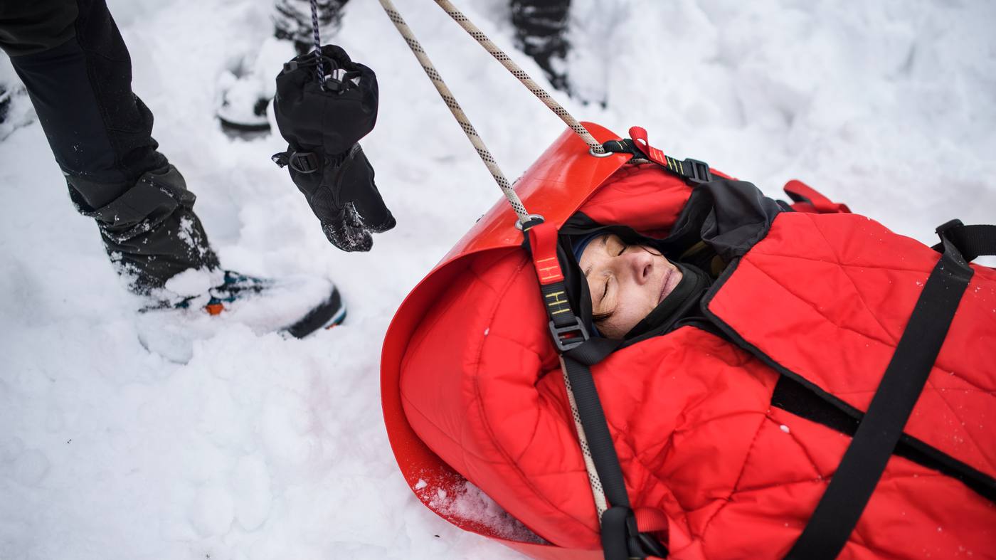 Mountain rescue team pulling an injured skier in a rescue sled